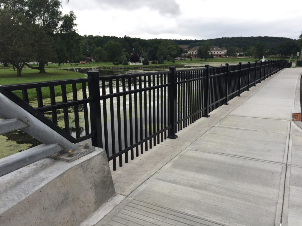 black alluminum fence along sidewalk surrounding a pond