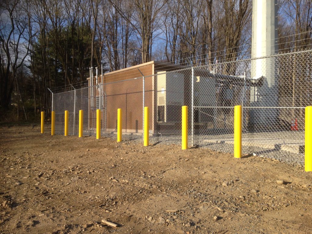 cell tower with chainlink security fence around it, equipped with barbed wire