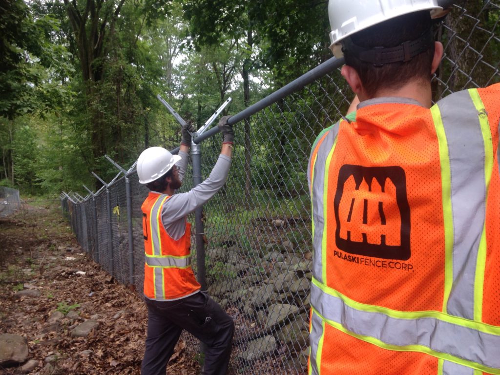 Workers installing a chainlink fence