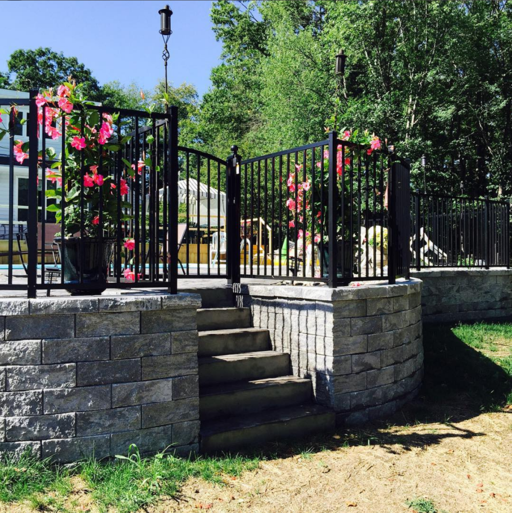Here is a black aluminum fence around a pool, installed along the brick patio.
