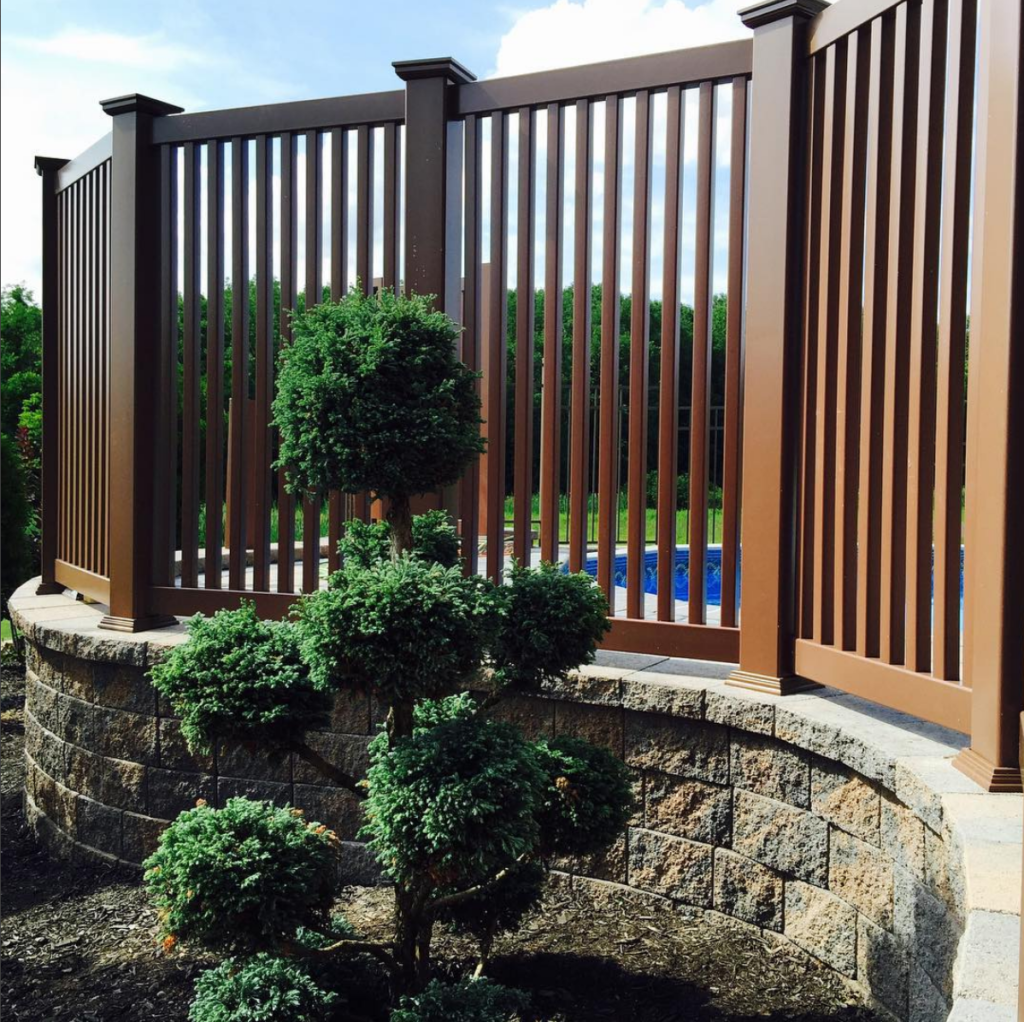 Here is a brown vinly fence around a pool, installed along the brick patio.