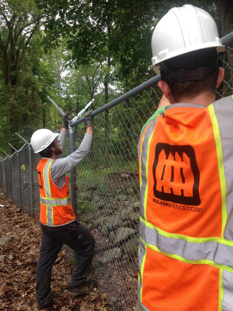 Workers installing a chainlink fence