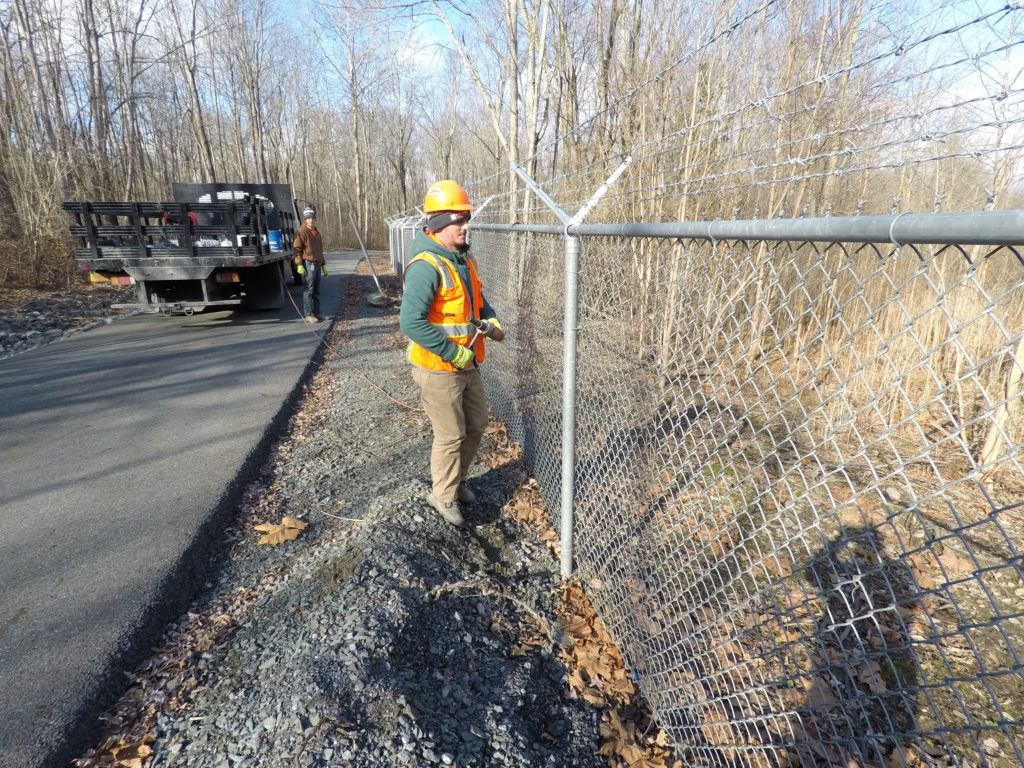 Chainlink Fence being installed, white truck with logo next to it.