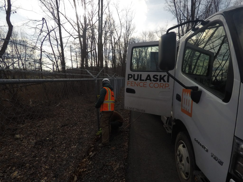 Chainlink Fence being installed, white truck with logo next to it.