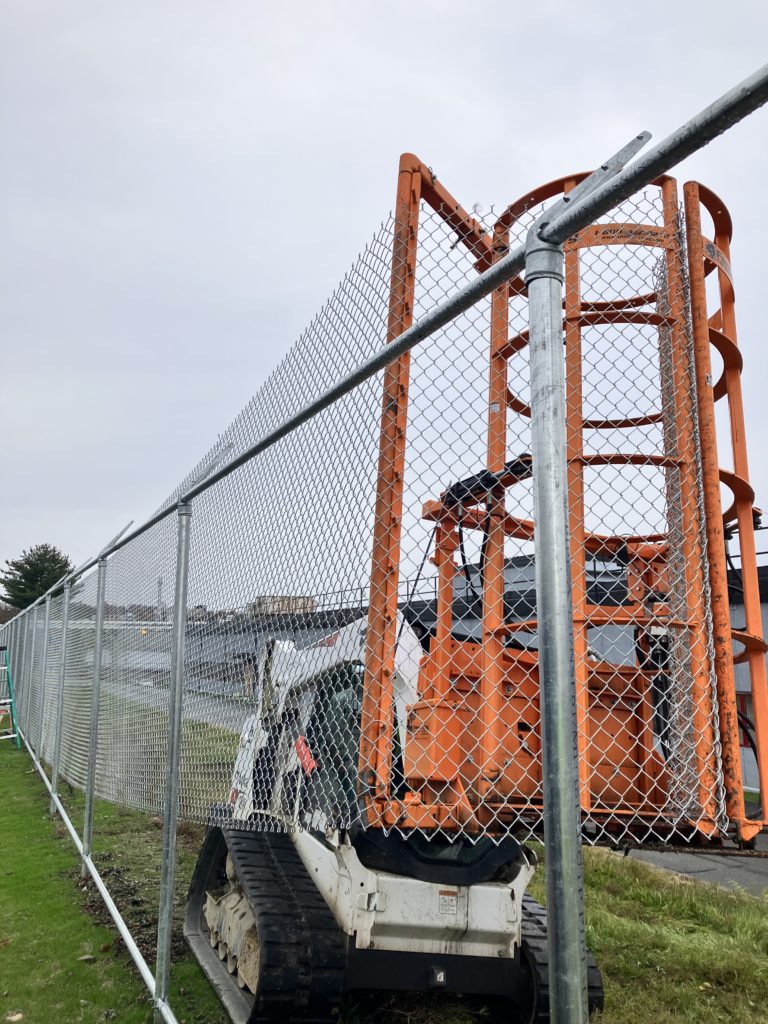 Bobcat skidsteer with EZG FenceHog attachment installing chainlink fence