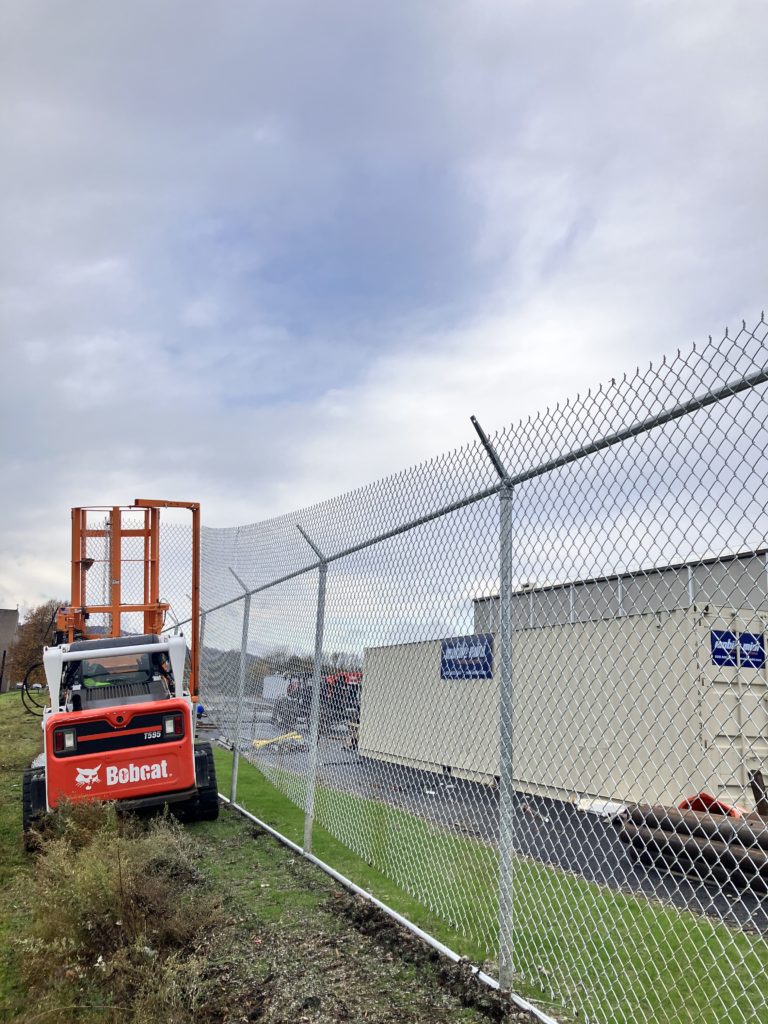 Bobcat skidsteer with EZG FenceHog attachment installing chainlink fence